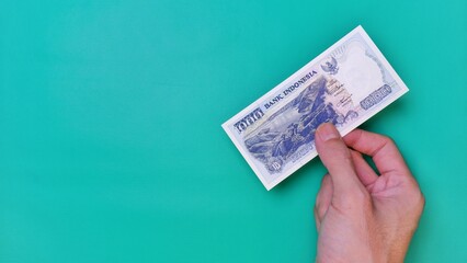 Indonesian Rupiah the official currency of Indonesia. Man's hand is making a payment. Male hand...