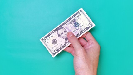 Man's hand is making a payment. Business Investment Economy Money Loan Saving Income and Finance concept. Male hand showing dollar bills on green background. Five Dollar. 5 USD. Prosperity concept.