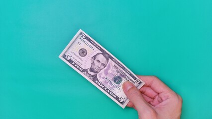 Man's hand is making a payment. Business Investment Economy Money Loan Saving Income and Finance concept. Male hand showing dollar bills on green background. Five Dollar. 5 USD. Prosperity concept.
