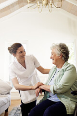 Making sure shes well taken care of. Shot of a smiling caregiver helping a senior woman in a...