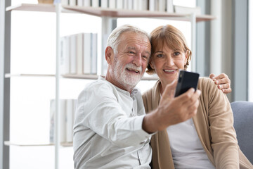 senior couple video call to someone or selfie from smartphone on sofa