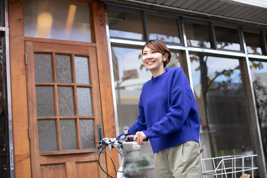 自転車を押して街を歩くミドル世代の日本人女性