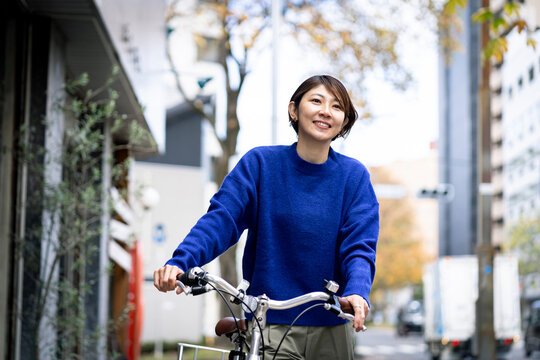 自転車を押して街を歩くミドル世代の日本人女性