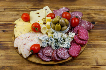 Antipasti platter with olives, cherry tomatoes, assortment of italian salami and cheese on a wooden table