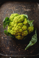 Ripe green cauliflower with leaves. Dark wood background.