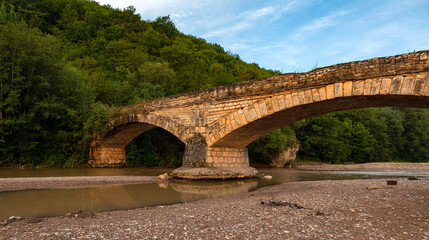 Fototapeta na wymiar An ancient stone bridge in the foothills of the Caucasus. Republic of Adygea