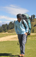 Full length of a young guy smiling while carrying parachute bag in mountain 