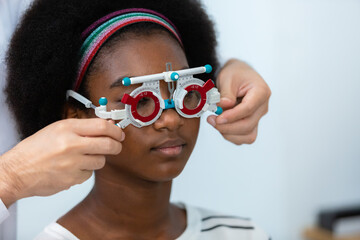 young woman african american wear trial frame eye test ophthalmological in optics clinic. woman...