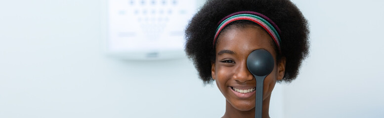 Young woman african american using occluder for eye test ophthalmological in optics clinic. woman checkup eye health with equipment ophthalmology medical in hospital. Banner copy space. - obrazy, fototapety, plakaty