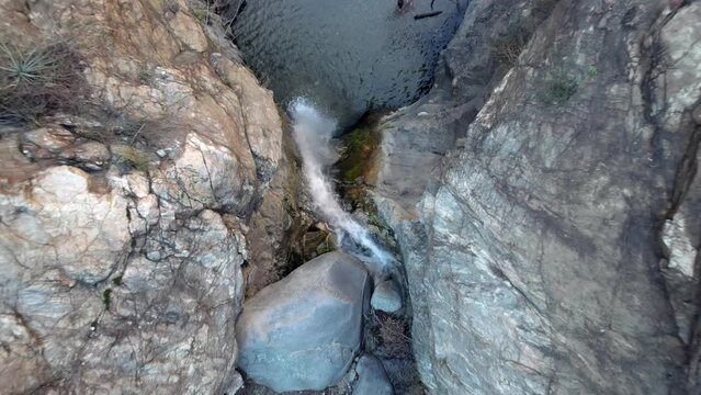 Topdown Eaton Canyon Falls, drone ascending motion revealing water flowing down Rocky Cliff Waterfall with tourists