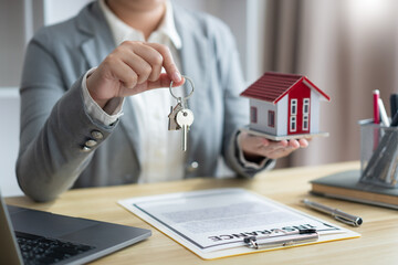 Insurance concept the real estate representative holding a house key on the right hand and the house model on the left hand