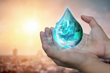 Blue Earth world with dripping water on two hand at wait on abstract city background. Water...