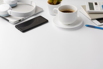 Creative white table with blank cellphone and supplies