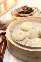 Delicious baozi, Chinese steamed meat bun is ready to eat on serving plate and steamer, close up, copy space product design concept.