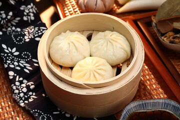 Delicious baozi, Chinese steamed meat bun is ready to eat on serving plate and steamer, close up, copy space product design concept.