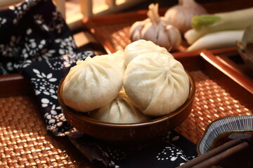 Delicious baozi, Chinese steamed meat bun is ready to eat on serving plate and steamer, close up, copy space product design concept.