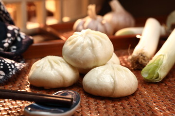 Fototapeta na wymiar Delicious baozi, Chinese steamed meat bun is ready to eat on serving plate and steamer, close up, copy space product design concept.