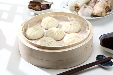 Delicious baozi, Chinese steamed meat bun is ready to eat on serving plate and steamer, close up, copy space product design concept.