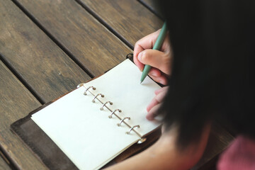 woman writing goal on notebook  at coffee shop outdoor space