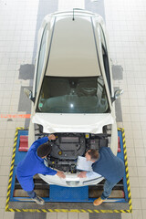 looking down on two mechanics working on car engine