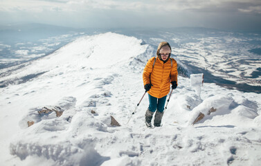 Fototapeta na wymiar Young woman climbing on the snowy mountain ridge