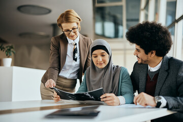 Young Muslim woman and her husband going through real estate offers with their agent in the office.