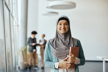 Portrait of happy Muslim businesswoman at corporate office looking at camera.