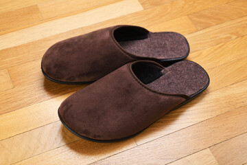 Brown home slippers on the parquet floor.Clear warm domestic sandal or sneakers. Bed shoes accessory footwear.