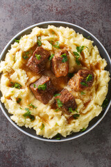 Greek sofrito is a dish consisting of tender cuts of beef slowly sauteed in a flavorful sauce served with mashed potatoes closeup in the plate on the table. Vertical top view from above