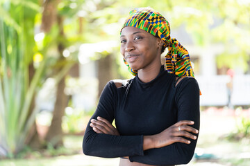 Smart young African beauty wearing a colorful, knotted scarf on her head and a black turtleneck...