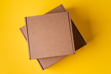 Beige cardboard boxes on yellow background, close up