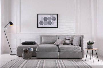 Cozy living room interior with comfortable grey sofa and beautiful picture