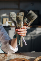 needlework. female hand holding different brushes