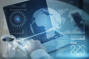 Close up of hand using laptop and cellphone with abstract global digital business interface on blurry background. Interface, chart and hud concept. Double exposure.