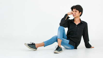 Portrait studio shot of Asian young LGBT gay bisexual homosexual glamour male fashionable model in casual outfit sitting crossed legs on floor closed eyes posing holding hand up on white background
