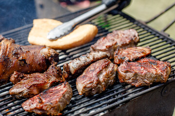 Close-up of meat steaks on the grill and barbecue with vegetables, corn.the chef holds the meat over the grill with tongs. food festival 