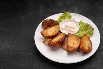 Homemade fried potatoes with sauce, on a dark background