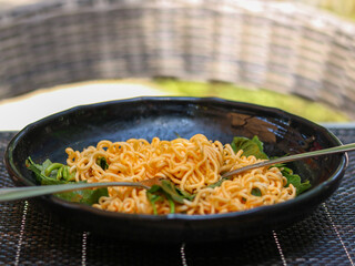 Yellow noodle in black plate.