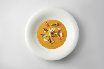 Close-up on pumpkin cream soup with crab in a white plate.