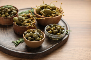 Delicious pickled capers and rosemary twigs on wooden table