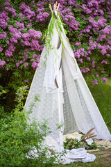 decorative wigwam house in nature. lilac in the park © Александр Ивчик
