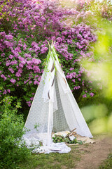 decorative wigwam house in nature. lilac in the park