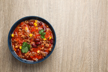 Bowl with tasty chili con carne on wooden table, top view. Space for text - obrazy, fototapety, plakaty