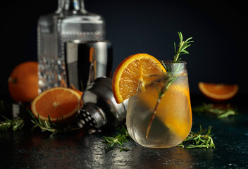 Cocktail gin tonic with ice, orange, and rosemary.