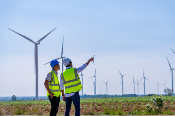 Engineer wearing uniform ,helmet hold document inspection work in wind turbine farms rotation to...
