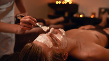 Cosmetician applying cosmetic cream of man in spa