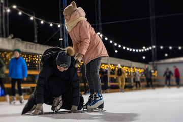 Fototapeta premium mother and daughter are skating, mother has fallen and is trying to get up