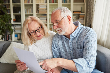 Senior couple reading an offer for retirement - obrazy, fototapety, plakaty