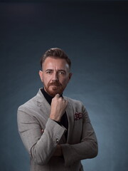 Obraz premium Portrait of a stylish elegant senior businessman with a beard and casual business clothes in photo studio isolated on dark background gesturing with hands