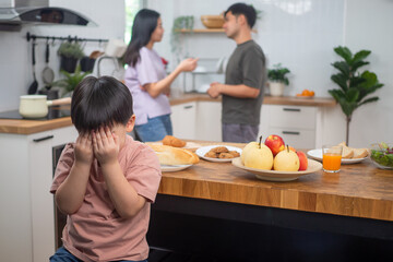 Family problems in divorce. The son covered his face, bored, stressed, sad to hear his parents arguing. The child has mental problems.